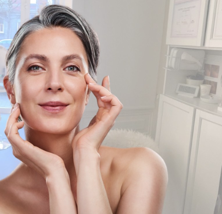 Femme aux cheveux gris, sereine, les mains sur le visage dans la cabine CmaDermo